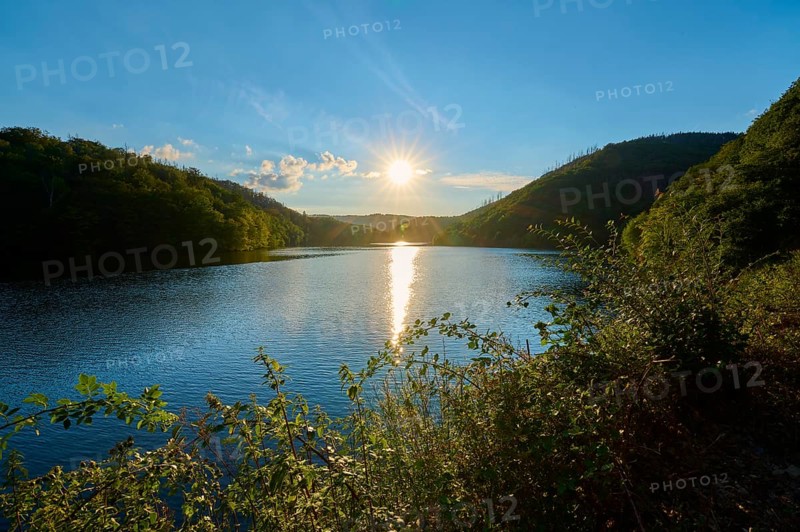 Sunset over a calm lake with green hills in the background, summer, Rursee, Obersee, Simmerath, Eifel National Park, North Rhine-Westphalia, Germany