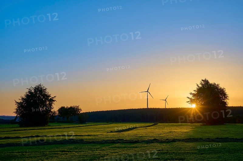 Wind turbines and trees at sunrise, the orange-coloured sky radiates warmth, summer, Rohren, Monschau, Eifel, North Rhine-Westphalia, Germany