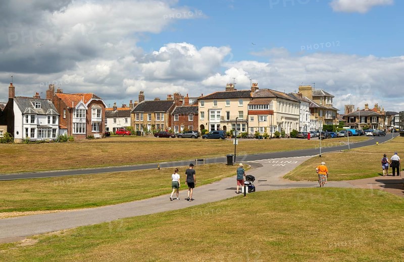 People walking on paths on grass area next to Queens Road, Southwold, Suffolk, England, Uk