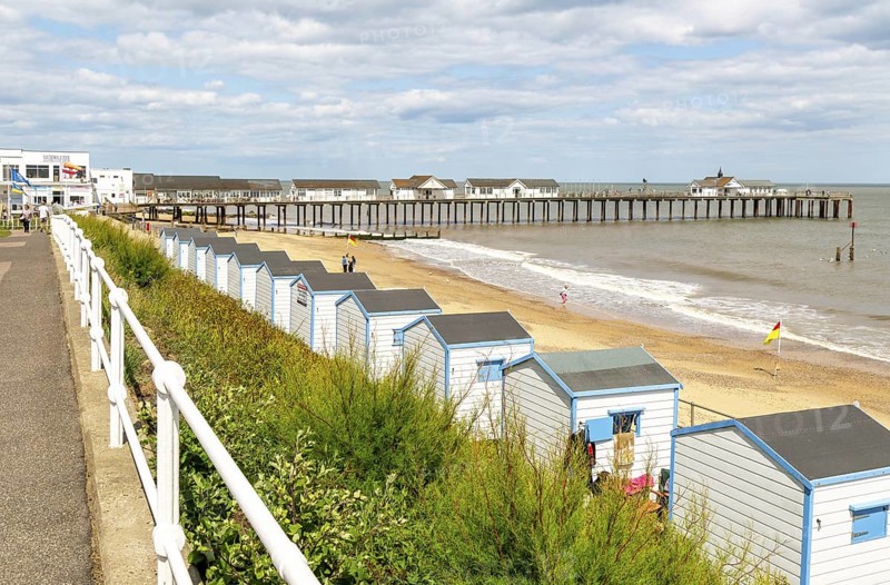 View over beach huts to sandy beach and pier, Southwold, Suffolk, England, UK