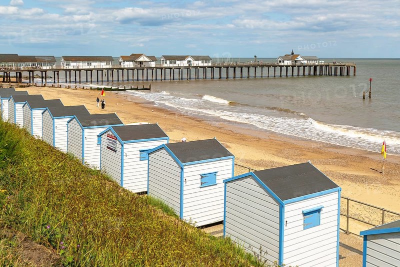 View over beach huts to sandy beach and pier, Southwold, Suffolk, England, UK