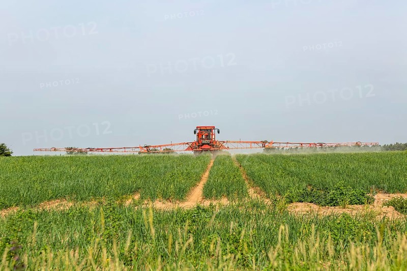 Tractor and crop sprayer spraying arable field, Capel St Andrew, Suffolk, England, UK