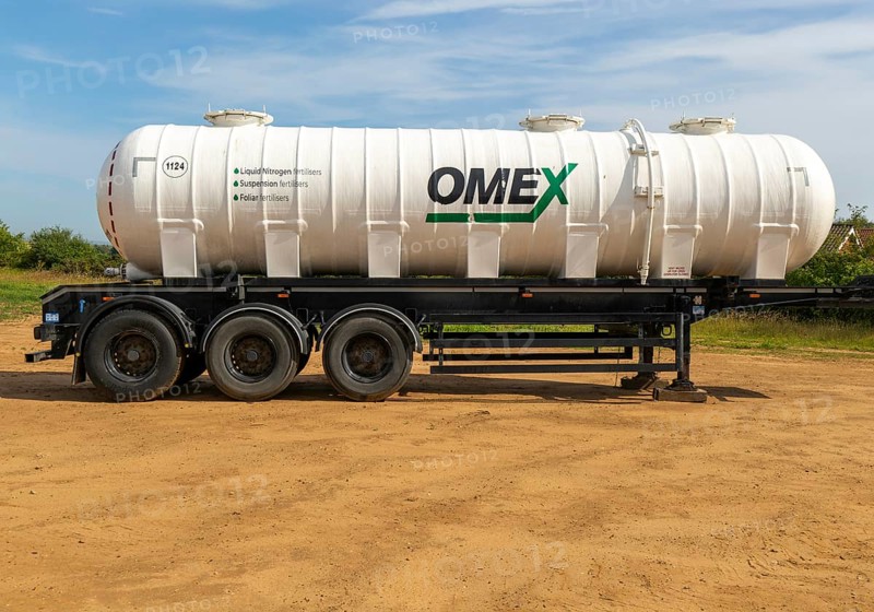 Omex fertiliser road tanker container waggon standing in field, Alderton, Suffolk, England, UK