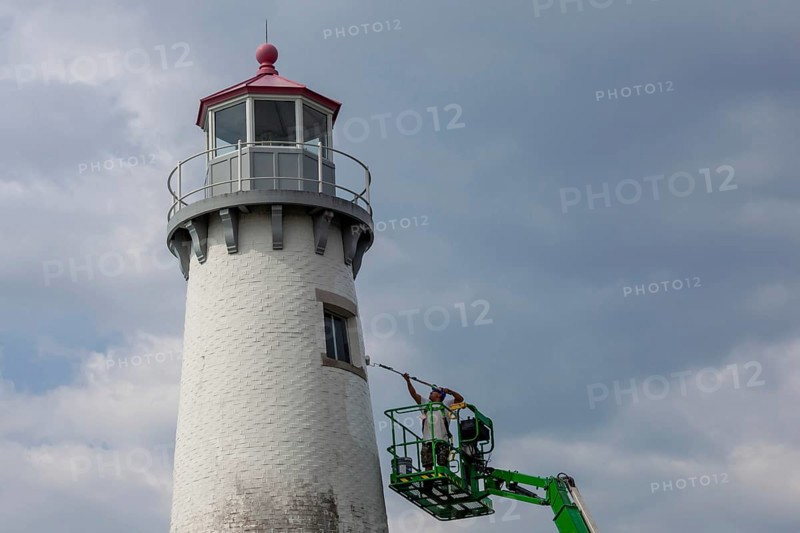 Detroit, Michigan - A worker on a lift paints the Milliken State Park Lighthouse. The lighthouse is on the Detroit River, near downtown Detroit