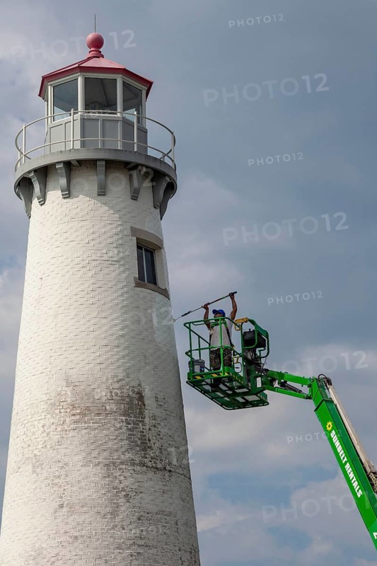 Detroit, Michigan - A worker on a lift paints the Milliken State Park Lighthouse. The lighthouse is on the Detroit River, near downtown Detroit