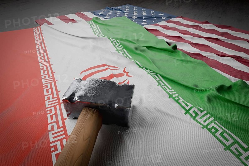 Large hammer resting on american and Iranian flags