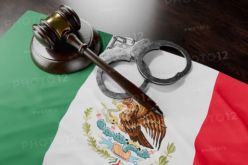 Gavel and handcuffs resting on mexican flag