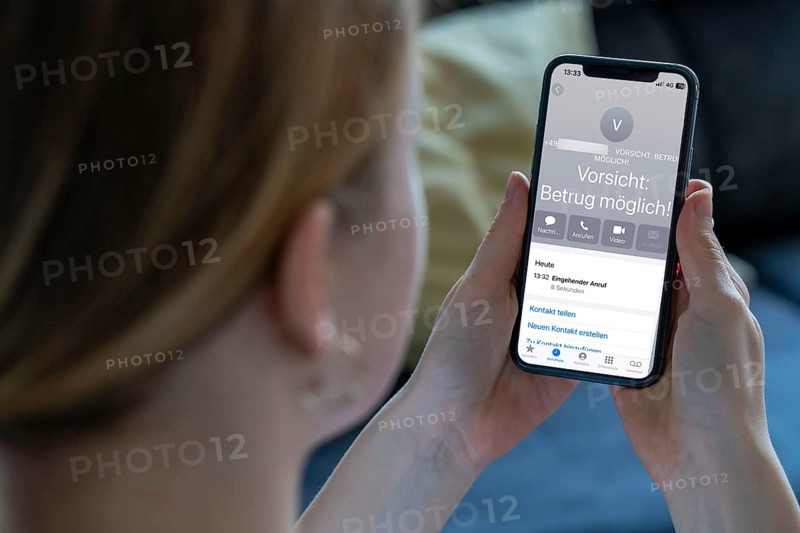 Symbolic image of mobile phone scam, warning of fraudulent calls, here the provider Vodafone, warns the mobile phone user that the caller may have a suspicious number that suggests fraud, spam protection system, the caller's number is stored in a database in which suspicious spam callers are stored, prevention of fraud attempts via mobile phone