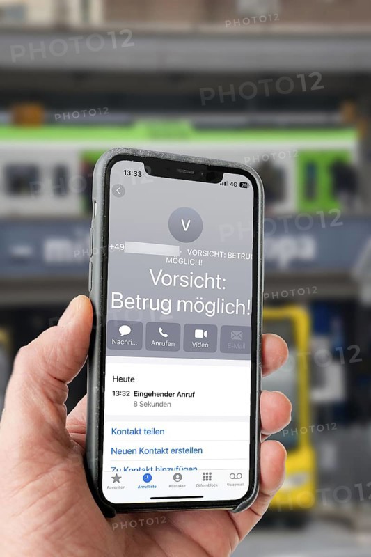 Symbolic image of mobile phone scam, warning of fraudulent calls, here the provider Vodafone, warns the mobile phone user that the caller may have a suspicious number that suggests fraud, spam protection system, the caller's number is stored in a database in which suspicious spam callers are stored, prevention of fraud attempts via mobile phone