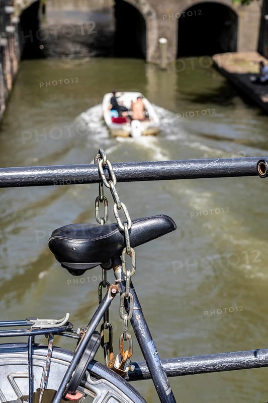 Cycling in the Netherlands, Utrecht, bicycle secured with a chain of steel links on a bridge over a canal, Netherlands