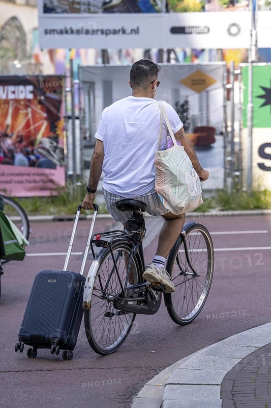 Cycling in the Netherlands, Utrecht, Cyclist pulling a wheeled suitcase behind him