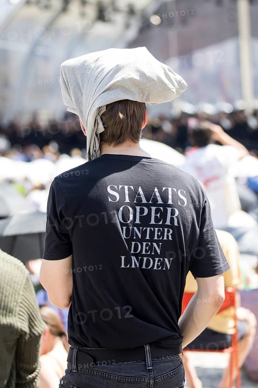 A visitor protects himself from the sun with fabric on his head at the Staatsoper fÃ¼r alle, a free open-air concert with conductor Christian Thielemann and the Staatskapelle Berlin on Berlin's Bebelplatz, Berlin, 22 June 2025