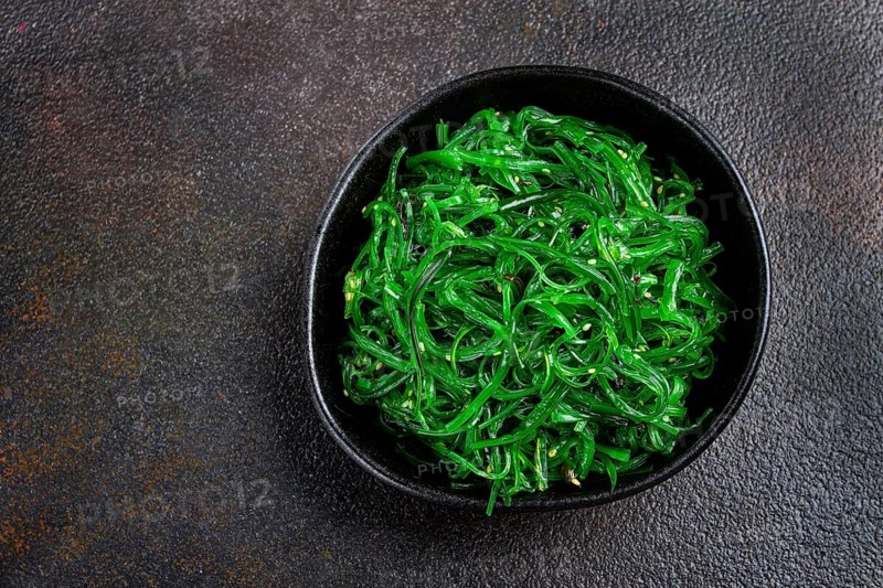 Chuka salad, made from fresh seaweed, with sesame dressing, served in a black bowl, with chopsticks
