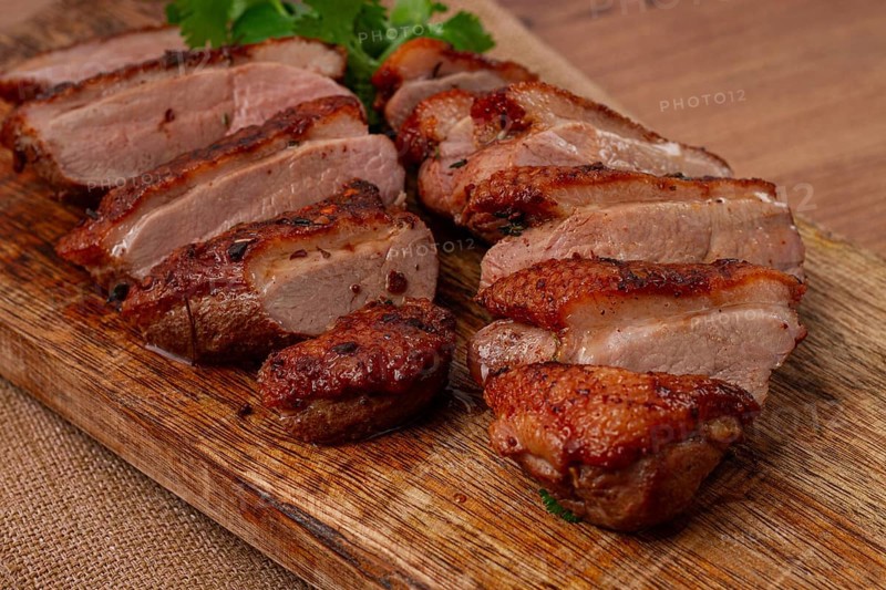 Roast duck breast, sliced, on a wooden chopping board, close-up, no people