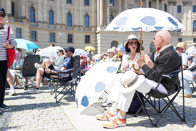 Two visitors under a parasol at the Staatsoper fÃ¼r alle, a free open-air concert with conductor Christian Thielemann and the Staatskapelle Berlin on Berlin's Bebelplatz, Berlin, 22 June 2025