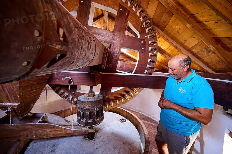 Man looking at the wooden gears of a windmill, Windmill, Antimacheia, Kos, Dodecanese, Greek Islands, Greece