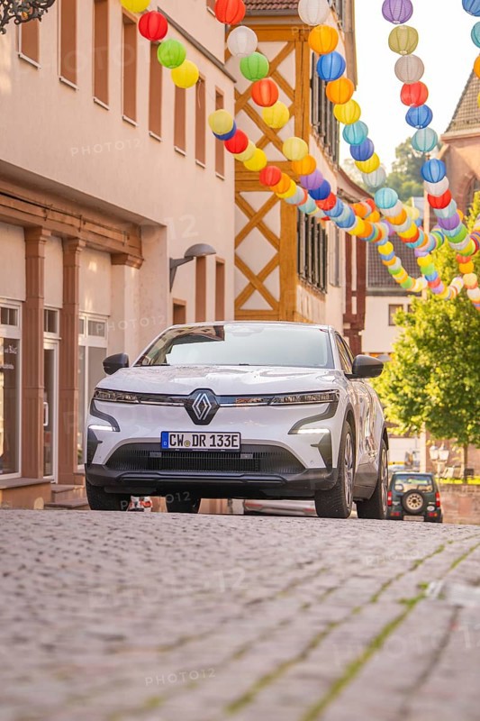 Car in a cobblestone alley decorated with colourful lanterns under bright daylight, Deer E, car sharing, electric car, Calw, Black Forest