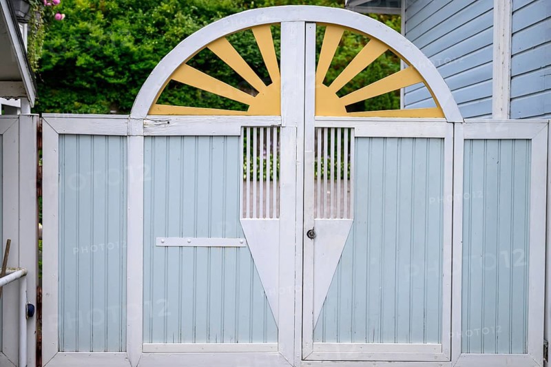 Street scene in the old town of Naantali, a decorative wooden gate in pastel shades with a semicircular sun motif radiates warmth, Naanatali, Varsinais-Suomi, Finland