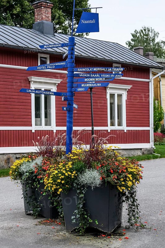 Street scene in the old town of Naantali, colorful signposts and flowers in front of a red wooden house create a nostalgic Scandinavian atmosphere, Naanatali, Varsinais-Suomi, Finland