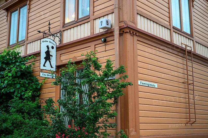 Street scene in the old town of Naantali, orange-painted wooden house with road signs and lush vegetation, on a quiet street, Naanatali, Varsinais-Suomi, Finland