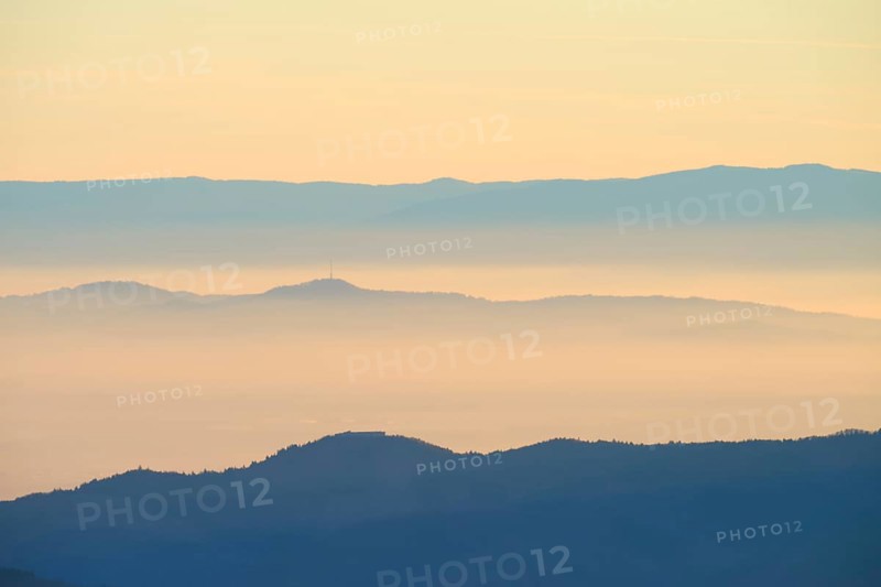 Gentle mountain silhouettes in morning haze with warm sunlight, looking towards the Rhine Valley, Hohneck, La Bresse, Vosges, France