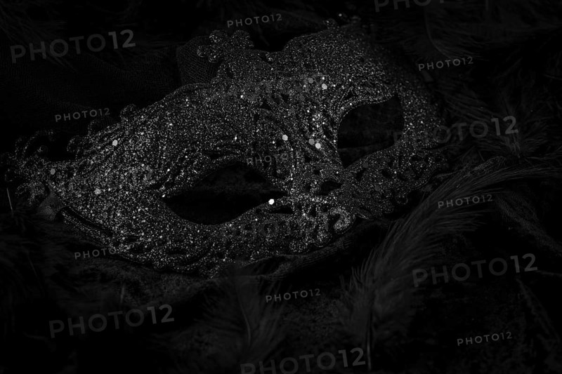 Black mask on dark background, contrasting carnival atmosphere
