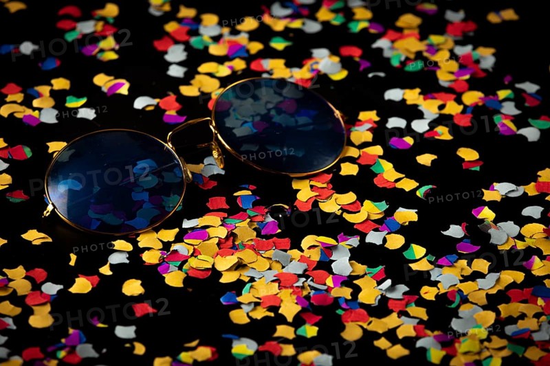 Sunglasses on colorful confetti against black background, Mardi Gras