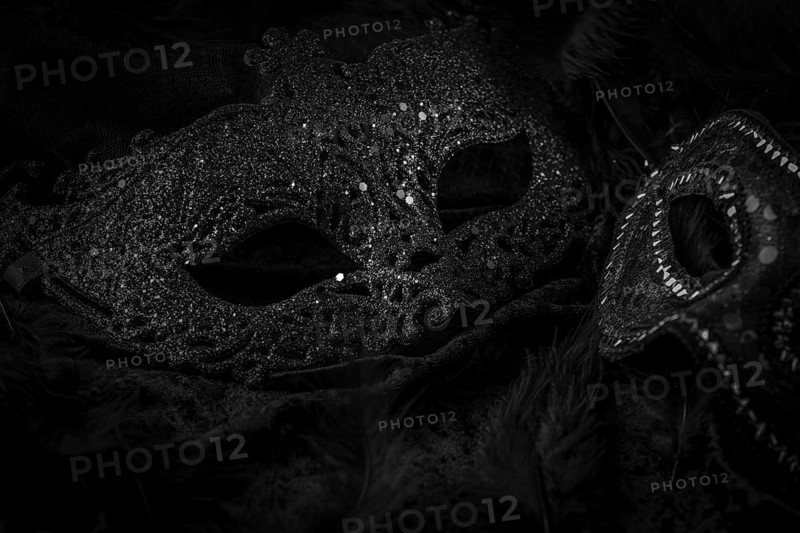 Black masks on a dark background, contrasting carnival atmosphere