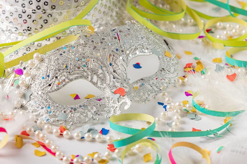 Silver carnival mask with pearls and colorful confetti on white background