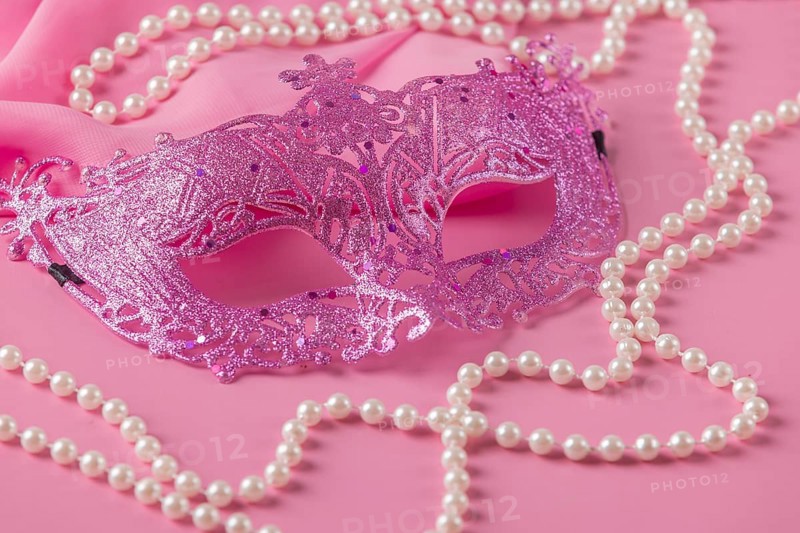 Glittering pink mask with pearl jewelry on a pink fabric