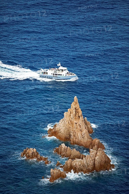 Visitors on an excursion boat look at bizarre rock formations at Capo Rosso, Piana, Corse-du-Sud department, west coast, Corsica, Mediterranean, France