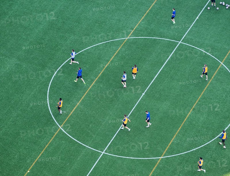 Players wearing colorful jerseys play soccer on a grass field from a bird's eye view from the tower of Helsinki Olympic Stadium, Finland