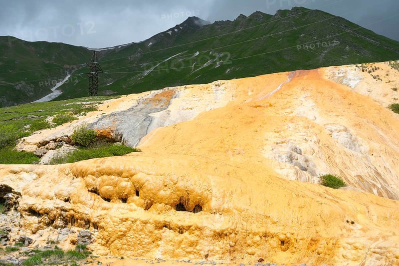 Yellow rocky landscape with green mountains and dark cloudy sky, Bidara Travertine, Travertine, Jvari Pass Trawertin Natural Monument, Cross Pass, Mtskheta-Mtianeti Province, Georgia