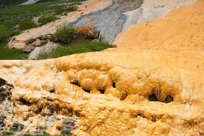 Close-up of an orange rock structure with surrounding vegetation and moss, Bidara travertine, Jvari Pass Trawertin natural monument, Cross Pass, Mtskheta-Mtianeti province, Georgia