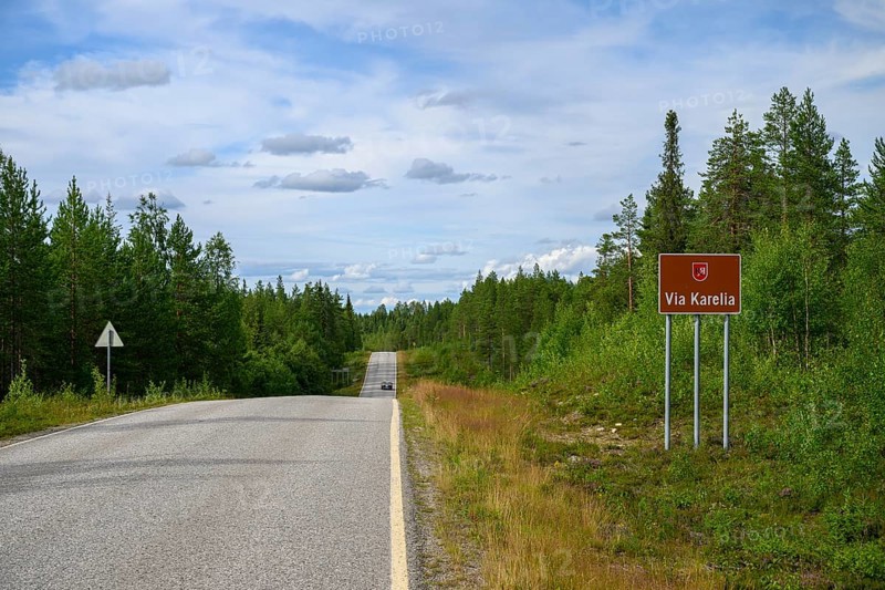 Via Karelia country road with a sign and surrounding trees under blue sky, Kuusamo, Lapland, Finland