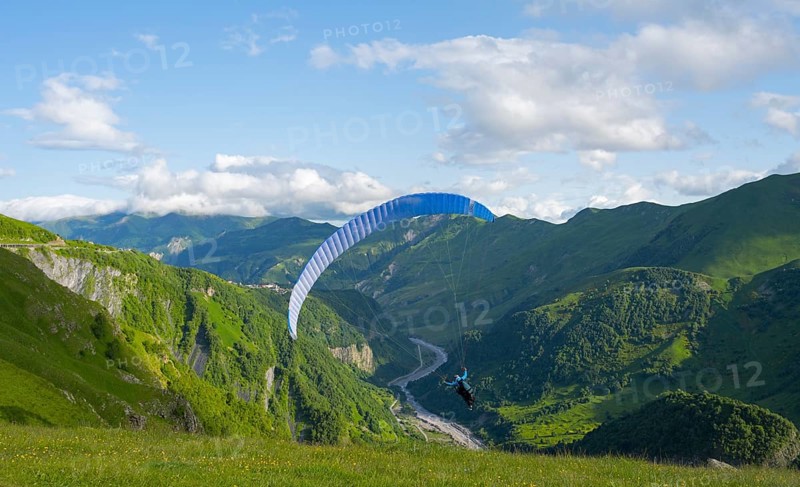 A paraglider soars over a green landscape with wide sky and valley views, paraglider, paraglider near Gudauri, White Aragvi River, Mtskheta-Mtianeti region, Georgian Military Route, High Caucasus, Georgia