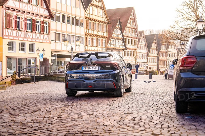Car drives through a historic street surrounded by traditional half-timbered houses and cobblestones, MG4 electric car, Deer e-Carsharing, Calw, Germany