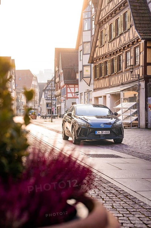 Black car in quiet old town with half-timbered houses and warm sunlight, MG4 electric car, Deer e-Carsharing, Calw, Germany