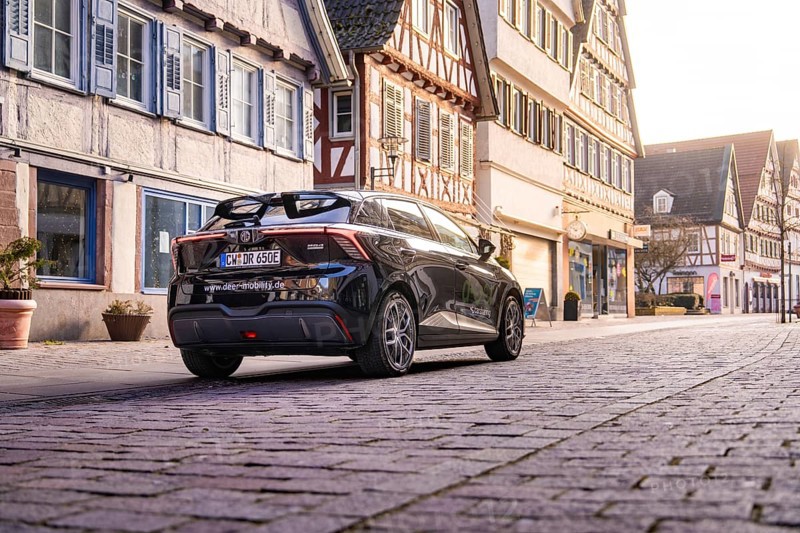 Car standing in front of half-timbered houses in a paved old town street under soft light, MG4 electric car, Deer e-Carsharing, Calw, Germany