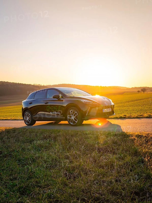 Black car parked on a country road surrounded by green fields when the sun is low, MG4 electric car, Deer e-Carsharing, Calw, Germany