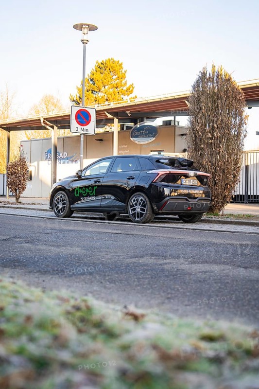 Car parked at the edge of a parking lot with trees and a building in the background, MG4 electric car, Deer E- Carsharing, Calw, Germany