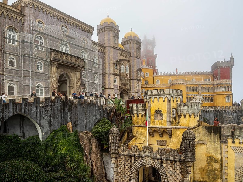 Tourists visiting the palace Palácio Nacional da Pena, foggy day, Sintra, Portugal