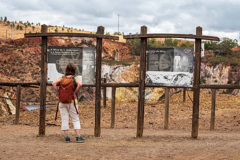 Woman reading explanatory panel, entrance to Mina de Sao Domingos, historic copper open-pit mine, Portugal
