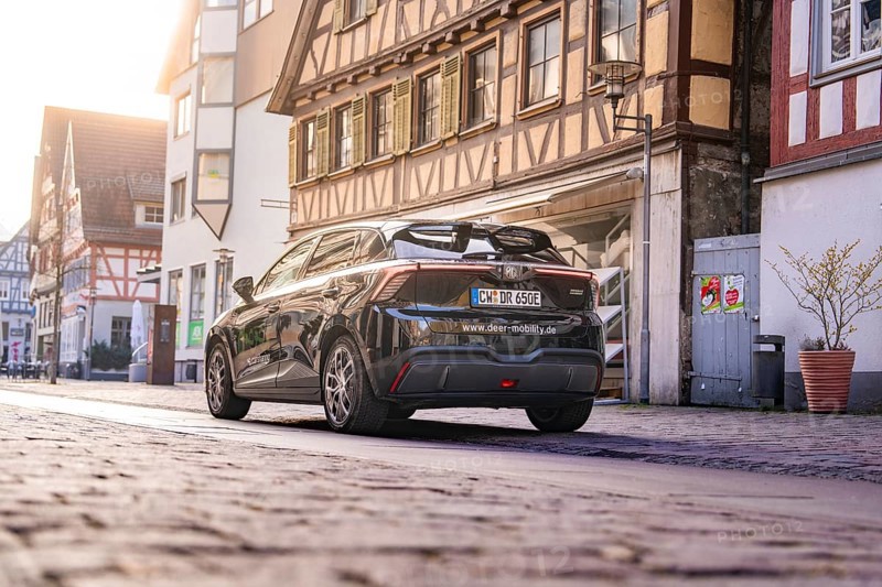 Black car from behind in a street with historic half-timbered houses in daylight, MG4 electric car, Deer e-Carsharing, Calw, Germany