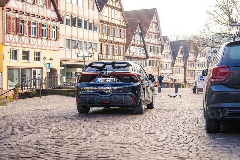 Car drives through a paved street surrounded by historic half-timbered houses, MG4 electric car, deer e-car sharing, Calw, Germany