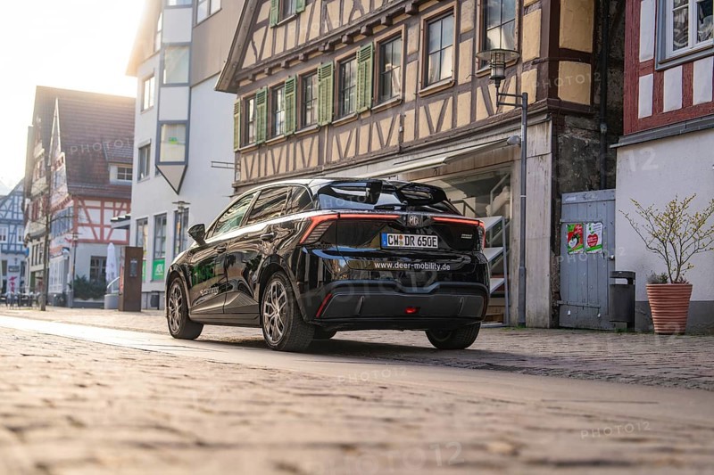 Rear view of a black car in front of historic half-timbered houses, captured in the evening mood, MG4 electric car, Deer e-Carsharing, Calw, Germany