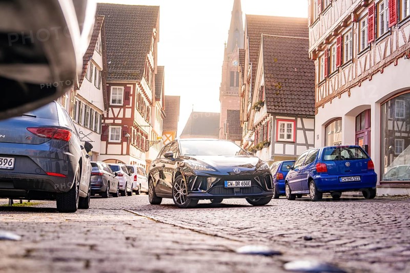 A modern car on a paved street in the old town, surrounded by half-timbered houses and parked cars, MG4 electric car, deer e-car sharing, Calw, Germany