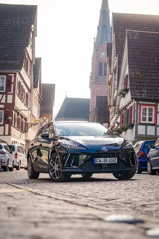 A car in a paved old town street with church and half-timbered houses, MG4 electric car, Deer e-Carsharing, Calw, Germany