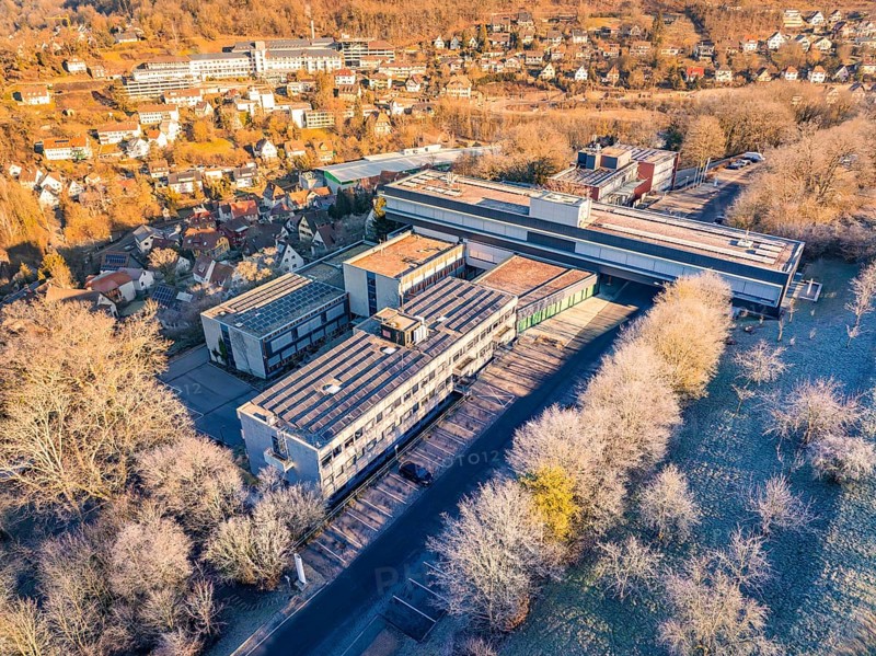 Aerial view of a large building complex surrounded by trees in an autumn landscape, MG4 electric car, Deer e-Carsharing, Calw, Germany