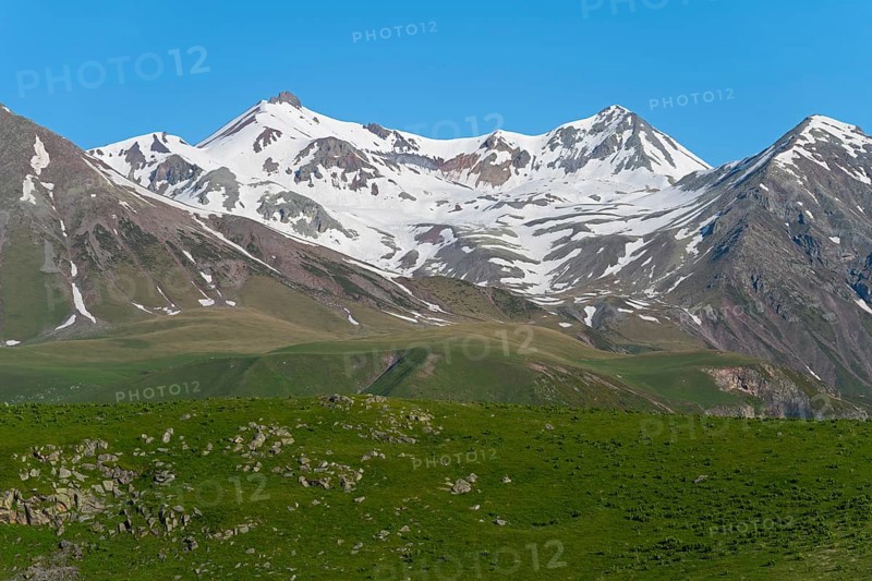 Impressive view of snow-capped mountains and green rocks, landscape between Kvesheti and Gudauri, Mtskheta-Mtianeti region, Georgian Military Route, High Caucasus, Georgia